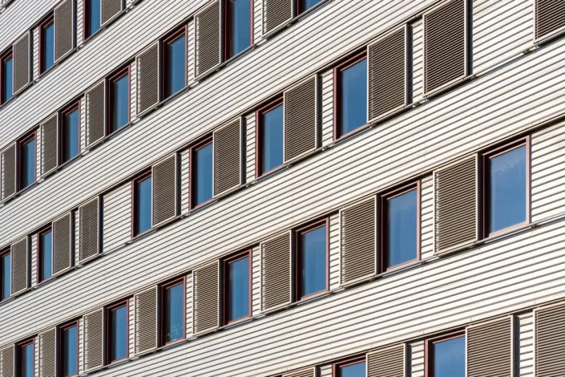 Geometric view of building facade featuring multiple windows and shutters.